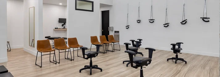Open room featuring chairs and chiropractic adjusting equipment.